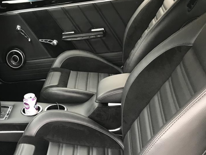 Classic Camaro front bucket seats with black upholstery and center console in a restored interior